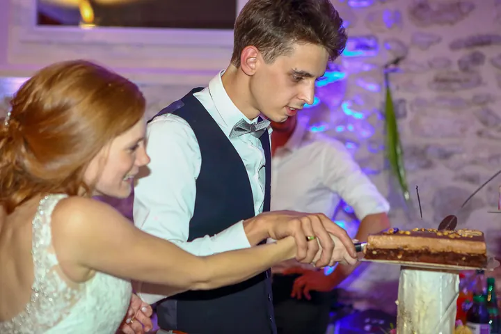 Mariés qui découpent le gâteau pendant la soirée