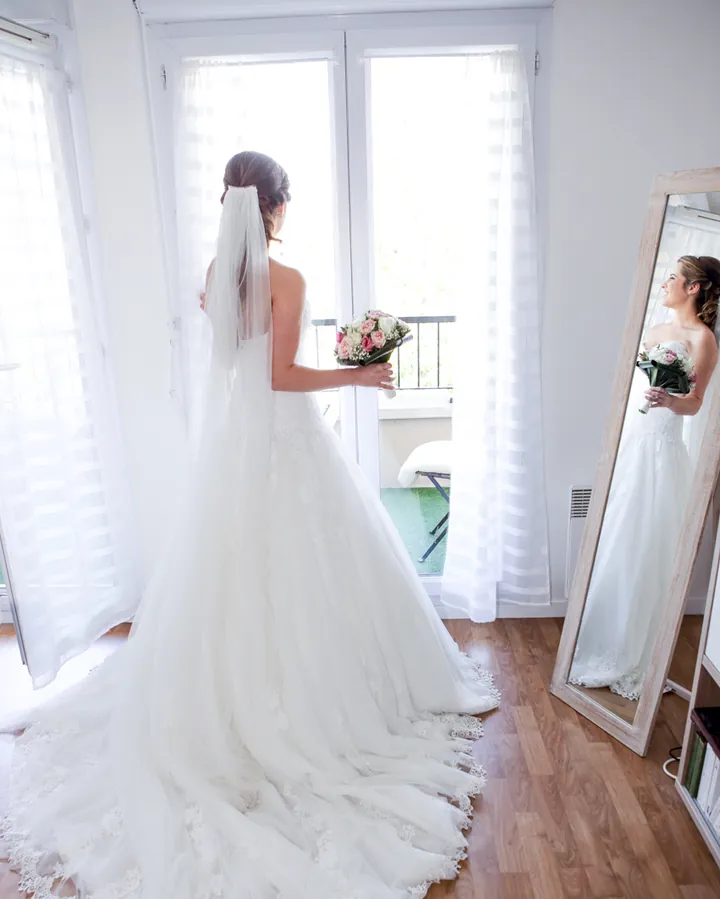 Mariée en robe devant le miroir pendant les préparatifs