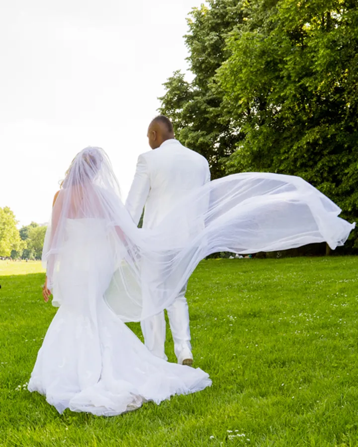 Mariée qui s'avance, voile au vent, vers sa cérémonie en extérieur